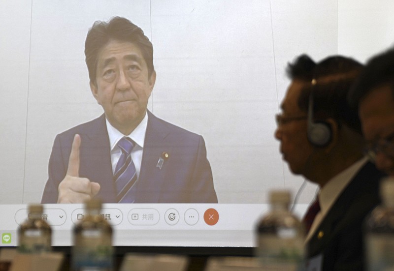 Former Japanese Prime Minister Shinzo Abe, seen on a screen, during a meeting in Taipei, Wednesday Dec. 1, 2021. China lashed out at Shinzo Abe Wednesday, Dec. 1, 2021, after the former Japanese prime minister warned of the serious security and economic consequences of any Chinese military action against the self-ruled island. (Kyodo News via AP)