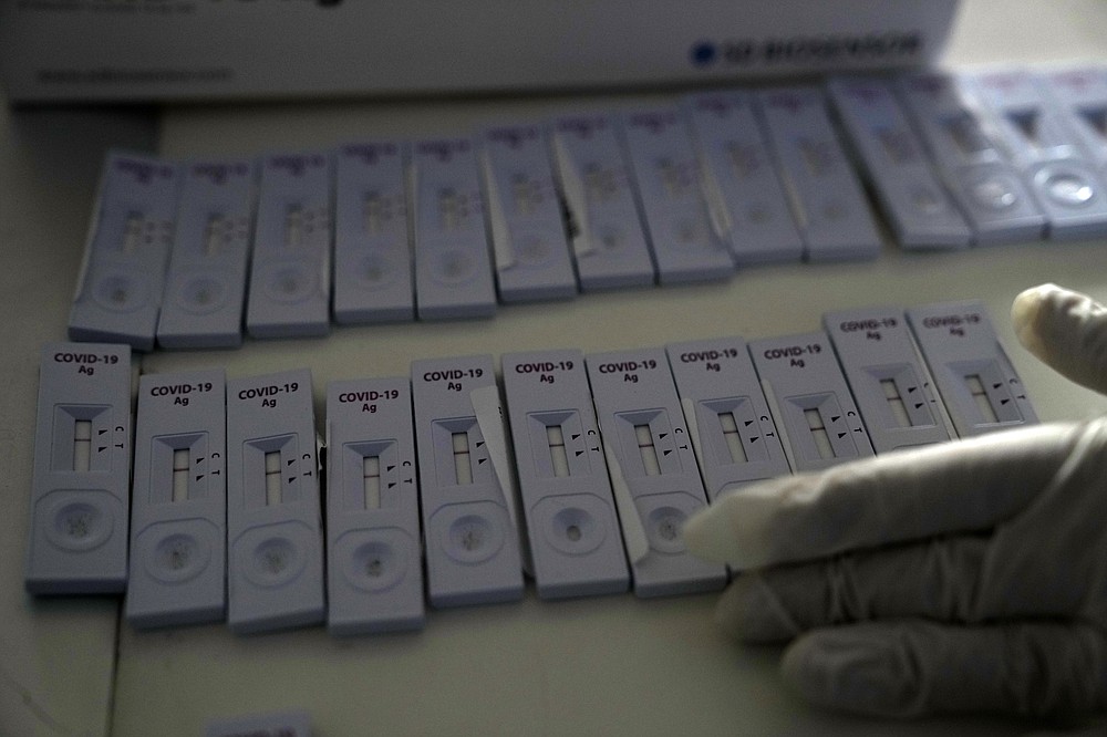 FILE - A member of the medical staff at the National Public Health Organisation (EODY) adjusts COVID-19 rapid tests in Athens, Greece, Monday, Nov. 15, 2021. The coronavirus&#x27;s omicron variant kept a jittery world off-kilter Wednesday Dec. 1, 2021, as reports of infections linked to the mutant strain cropped up in more parts of the globe, and one official said that the wait for more information on its dangers felt like &amp;#x201c;an eternity.&amp;#x201d; (AP Photo/Thanassis Stavrakis, File)
