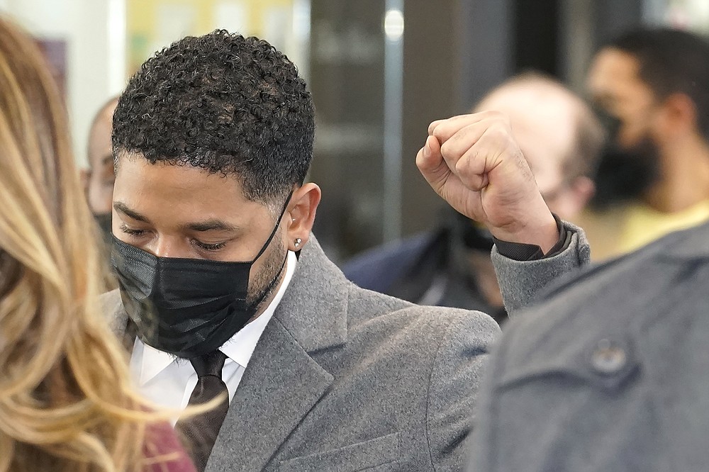 Actor Jussie Smollett raises his fist when asked how he was doing while walking through the Leighton Criminal Courthouse lobby on day four of his trial Thursday, Dec. 2, 2021, in Chicago. Smollett is accused of lying to police when he reported he was the victim of a racist, anti-gay attack in downtown Chicago nearly three years ago. (AP Photo/Charles Rex Arbogast)