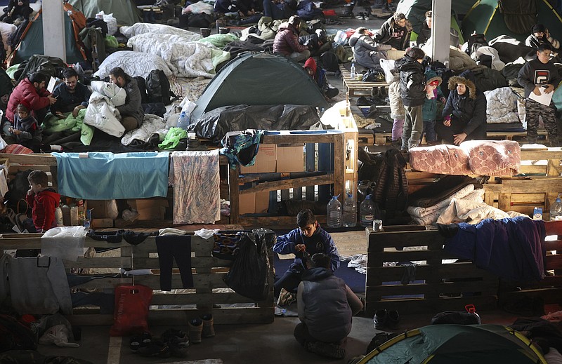 Migrants settle in the logistics center of the checkpoint &quot;Bruzgi&quot; at the Belarus-Poland border near Grodno, Belarus, Wednesday, Dec. 1, 2021. The West has accused Belarusian President Alexander Lukashenko of luring thousands of migrants to Belarus with the promise of help to get to Western Europe to use them as pawns to destabilize the 27-nation European Union in retaliation for its sanctions on his authoritarian government. Belarus denies engineering the crisis. (Oksana Manchuk/BelTA via AP)