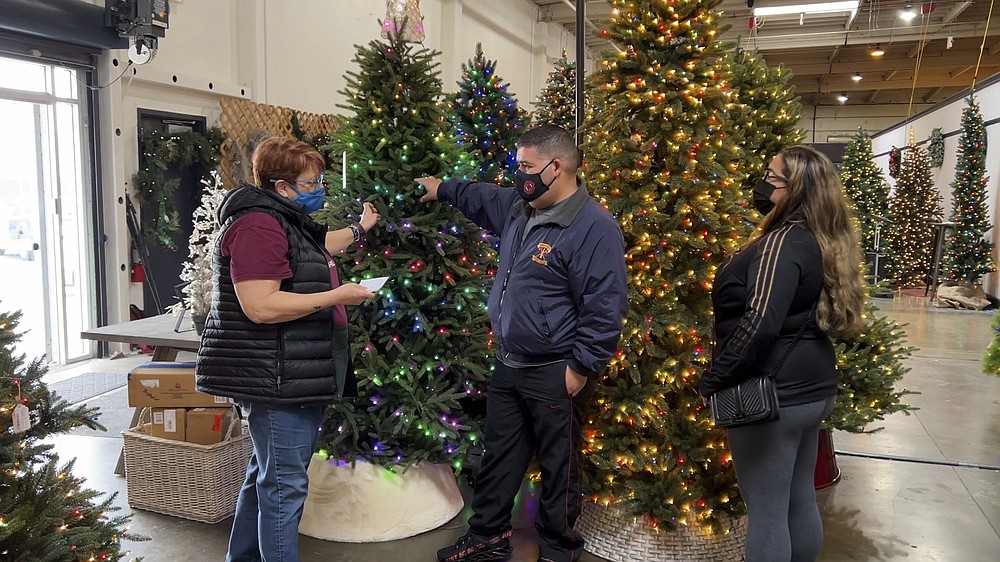 David Cruise discusses artificial Christmas trees with a salesperson at the Balsam Hill showroom in Burlingame, Calif. on Nov. 19, 2021. Extreme weather and supply chain disruptions have led to shortages and higher prices for both real and artificial Christmas trees this year. (AP Photo/Terry Chea)
