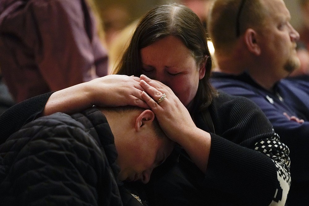 Aiden Watson, who was injured at Oxford High School, attends a vigil with his mother at LakePoint Community Church in Oxford, Mich., late Tuesday, Nov. 30, 2021. Authorities say a 15-year-old sophomore opened fire at Oxford High School, killing three students and wounding several others, including a teacher. (AP Photo/Paul Sancya)