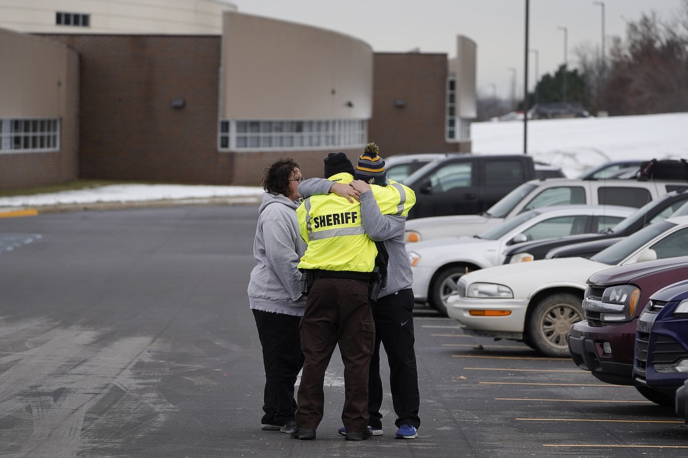 An Oakland County Sheriff&#x27;s deputy hugs family members of a student in the parking lot of Oxford High School in Oxford, Mich., Wednesday, Dec. 1, 2021. A 15-year-old sophomore opened fire at the school, killing several students and wounding multiple other people, including a teacher. (AP Photo/Paul Sancya)