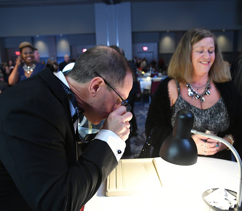 April Gilbert, right, starts to realize that her ice cube contained a diamond while Toddy Pitard, owner of Lauray’s — The Diamond Center examines the stone during Ice on Ice at Oaklawn Racing Casino Resort on Thursday. - Photo by Tanner Newton of The Sentinel-Record