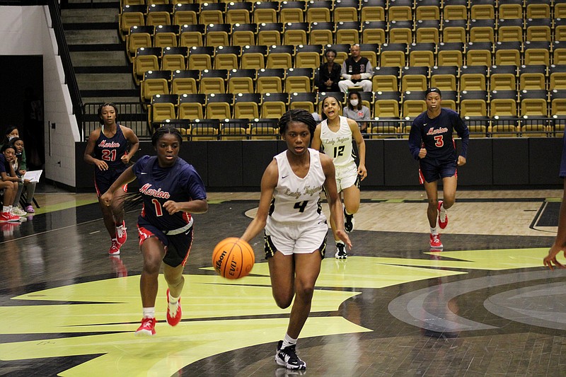 Hot Springs sophomore Kyabra Lomax (4) drives past Marion sophomore Ny'Asia Jackson (1) during Friday's loss at Trojan Arena. - Photo by James Leigh of The Sentinel-Record