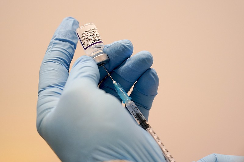 A Pfizer COVID-19 vaccine is prepared at Swaminarayan School vaccination centre, in London, Saturday, Dec. 4, 2021. Britain says it will offer all adults a booster dose of vaccine within two months to bolster the nation's immunity as the new omicron variant of the coronavirus spreads. New measures to combat variant came into force in England on Tuesday, with face coverings again compulsory in shops and on public transport. (AP Photo/Alberto Pezzali)