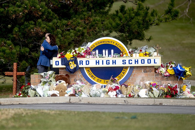 Gov. Gretchen Whitmer embraces Oakland County Executive Dave Coulter as the two leave flowers and pay their respects Thursday morning, Dec. 2, 2021 at Oxford High School in Oxford, Mich.  A 15-year-old boy has been denied bail and moved to jail after being charged in the Michigan school shooting that killed four students and injured others.(Jake May/The Flint Journal via AP)