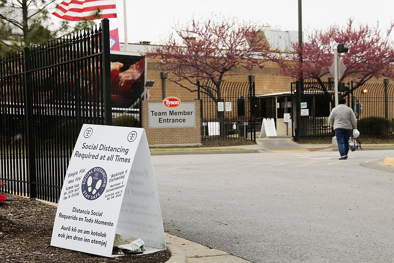 In this image from the Howard Center for Investigative Journalism at the University of Maryland's Philip Merrill College of Journalism, a Tyson employee walks into the team member entrance at the Berry Street location in Springdale, Ark., on April 20, 2021. A sign in their path reads &quot;Social Distancing Required at all Times&quot; written in English, Spanish and Marshallese. (Mary Hennigan/University of Arkansas via AP)