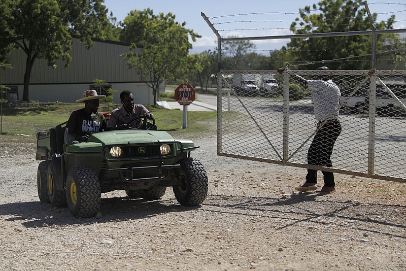 Workers ride out of the gate of the Christian Aid Ministries headquarters in Titanyen, north of Port-au-Prince, Haiti, Monday, Dec. 6, 2021. The religious group based in Ohio said that three more hostages were released on Sunday, while another 12 remain abducted in Haiti. The group provided no further details. (AP Photo/Odelyn Joseph)