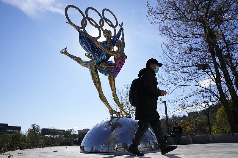 A visitor to the Shougang Park walks past the a sculpture for the Beijing Winter Olympics in Beijing, China, Tuesday, Nov. 9, 2021. China on Monday, Dec. 6, 2021, threatened to take &quot;firm countermeasures&quot; if the U.S. proceeds with a diplomatic boycott of February's Beijing Winter Olympic Games. (AP Photo/Ng Han Guan)
