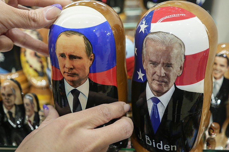 A customer shows to photographer a traditional Russian wooden dolls called Matreska of Russian President Vladimir Putin, center, and U.S. President Joe Biden, center right, at a souvenirs store in Moscow, Russia, Monday, Dec. 6, 2021. The Kremlin says President Joe Biden and Russian President Vladimir Putin will speak in a video call Tuesday. (AP Photo/Pavel Golovkin)