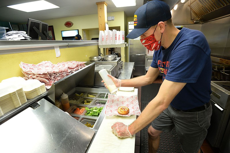 Chase Feltner, co-owner of Feltner Brothers, prepares food April 23, 2021, at the restaurant in Fayetteville. The city's Board of Health agreed Wednesday people should wear masks in public regardless of whether a mandate is in place. (File photo/NWA Democrat-Gazette/Andy Shupe)