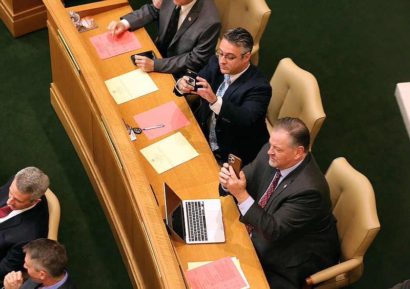 On Wednesday, Rep. Spencer Hawks (top left) and Rep. Brian Evans (right) take photos of the voting board after the passage of HB1001, which would reduce state income taxes, during the House session, Dec. 8, 2021, at the state Capitol in Little Rock. 
More photos at www.arkansasonline.com/129session/
(Arkansas Democrat-Gazette/Thomas Metthe)