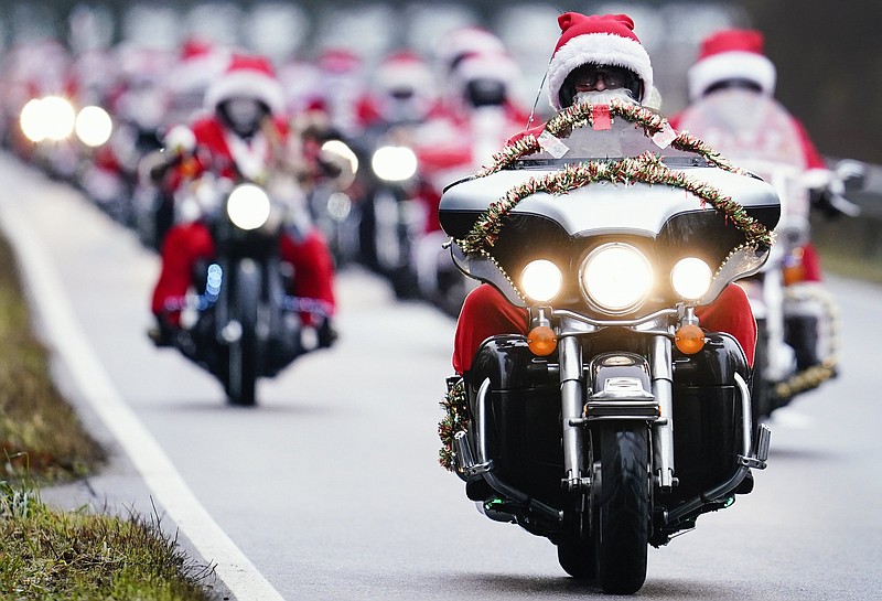 Motorcyclists of the 'Harley Davidson riding Santas' dressed up as Santa Clauses ride along a country road in Germersheim, Germany, Monday, Dec. 6, 2021. On a route from Germersheim to Speyer, the Santas want to deliver 18 large jute sacks with around 2,000 gift packages to schools, daycare centers and retirement homes, among other places, and thus also draw attention to their fundraising campaign. (Uwe Anspach/dpa via AP)