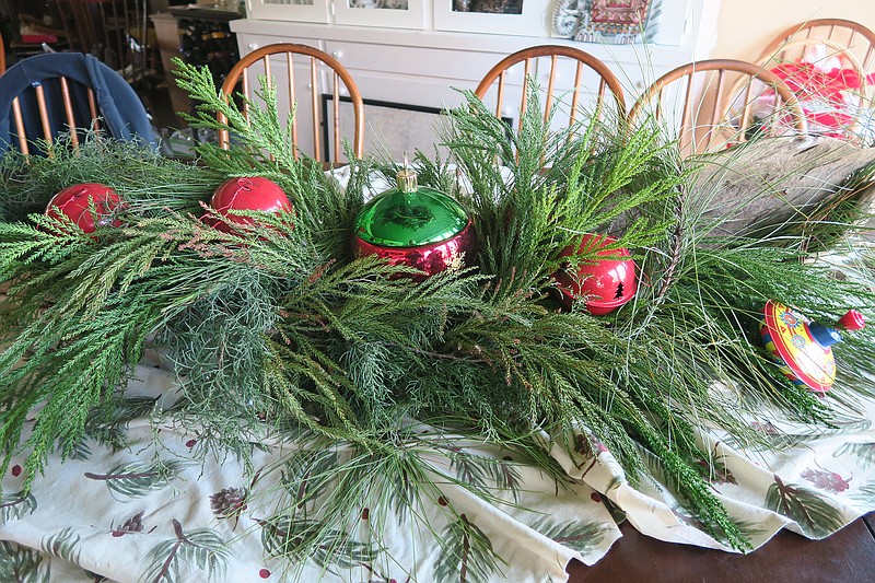 Carefully pruned sections of evergreen make a cheerful table swag when bound together and topped with bright ornaments. (Special to the Democrat-Gazette/Janet B. Carson)