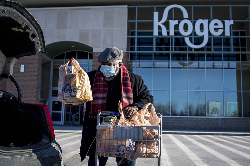 FILE - A shopper loads his car with groceries at the Kroger in Novi, Mich on Jan. 23, 2021.  Kroger says, Tuesday, Dec. 14,  it is modifying some of its COVID-19 policies. Unvaccinated workers will no longer receive certain COVID-19 leave benefits if they get the virus, and some who refuse the shot will also have to pay a monthly health insurance surcharge. (Nic Antaya/Detroit News via AP)