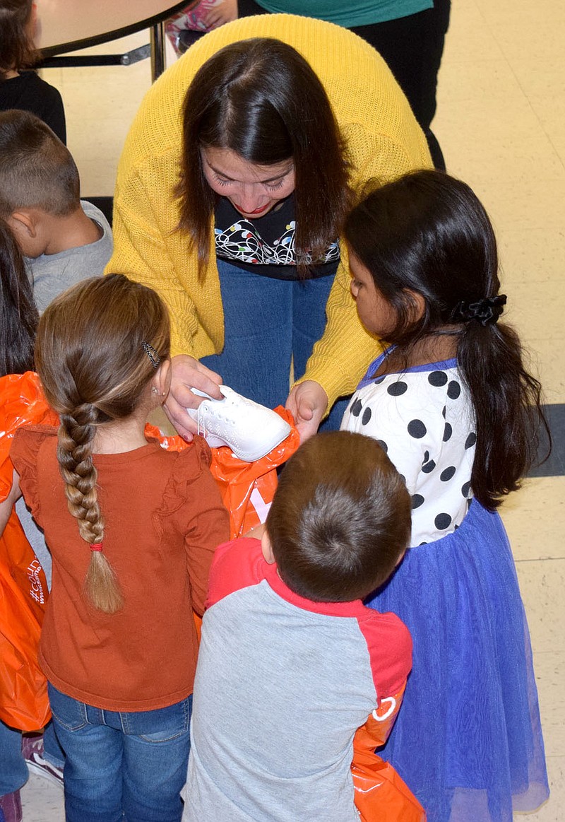 Westside Eagle Observer/MIKE ECKELS
Brittney Wilmoth (upper center) pulls out a few items from the bag of one of her students during the Samaritan's Feet International Shoes 4 Kids giveaway at Northside Elementary in Decatur Thursday morning.