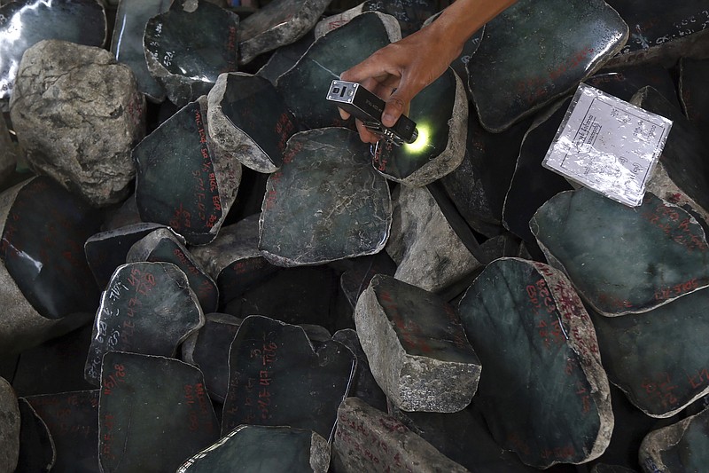 FILE - A merchant examines a jade stone displayed at the Gems Emporium in Naypyitaw, Myanmar on Nov. 13, 2018. Human rights activists are lobbying major jewelers to stop buying gems sourced in Myanmar as a way to exert pressure on Myanmar&#x2019;s military leaders by limiting profits from the country&#x2019;s lucrative mining industry. (AP Photo/Aung Shine Oo, File)