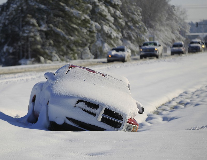 A vehicle abandoned by its driver lies buried in snow along the median of Maumelle Boulevard on Dec. 26, 2012.  A historic Christmas snow storm dropped almost of a foot of snow in the middle of Arkansas. (Democrat-Gazette file photo)