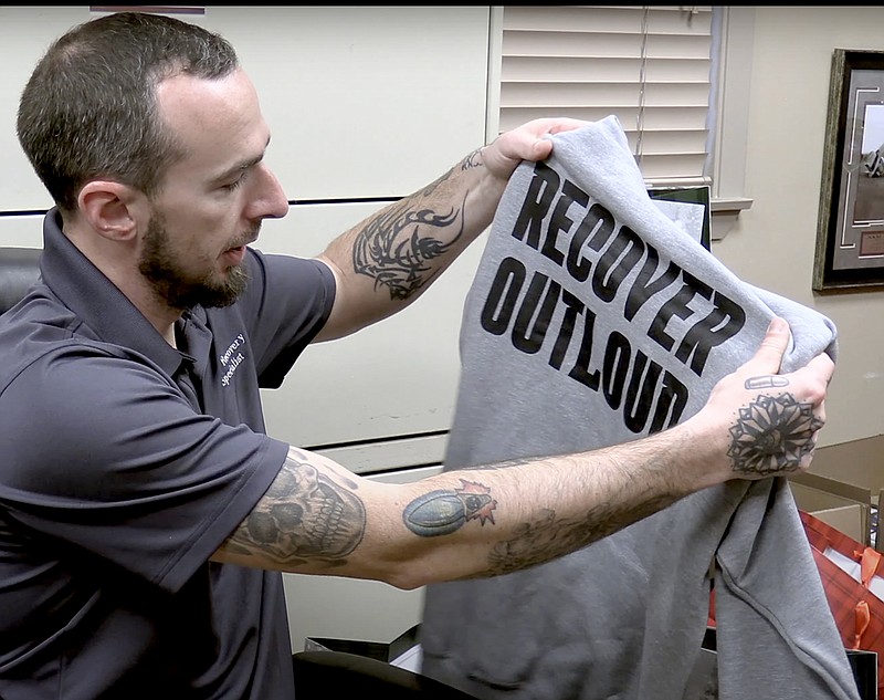 Sean Willits, Hot Springs Police Department peer recovery specialist, displays the hoodie included in the Christmas In Recovery gift bags. - Photo by Donald Cross of The Sentinel-Record