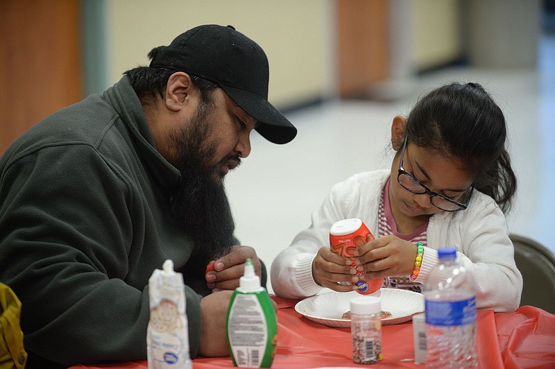NWA Democrat-Gazette/ANDY SHUPE
Frailan Riklon (left) helps his daughter, Chayann Riklon, 7, Friday, Dec. 20, 2019, as the two decorate Christmas cookies during the University of Arkansas for Medical Science Healthy Start and Marshallese Educational Initiative Holiday Celebration at Center for Nonprofits at the JTL Shop in downtown Springdale. The event featured free haircuts, cookie decorating and time with Santa Claus. Check out nwaonline.com/191221Daily/ for todays photo gallery.
