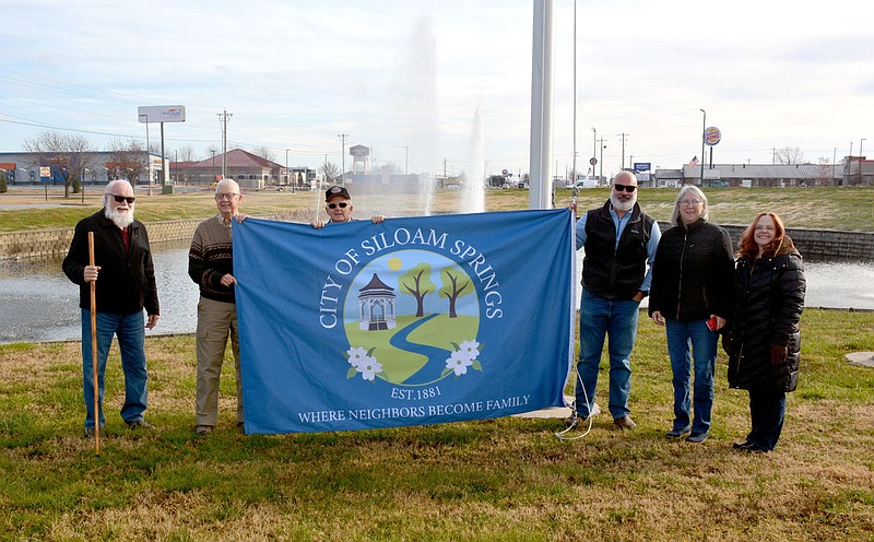 Marc Hayot/Herald-Leader Bob Coleman (left); Jerry Cavness; Stanley Church; Jon Boles, Parks and Recreation director; Kathy Turner and Patti Eiland pose in front of the new Siloam Springs city flag on Monday. The City Flag Redesign Committee presented the new flag at the city board meeting on Nov. 16 where city directors praised the efforts of the committee's work.