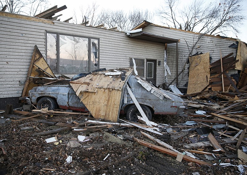 Debris covers a vehicle beside a damaged home in Rudd, Iowa, on Thursday, Dec. 16, 2021, after a band of severe weather with a tornado hit the small north central Iowa town late Wednesday. (Bryon Houlgrave/The Des Moines Register via AP)
