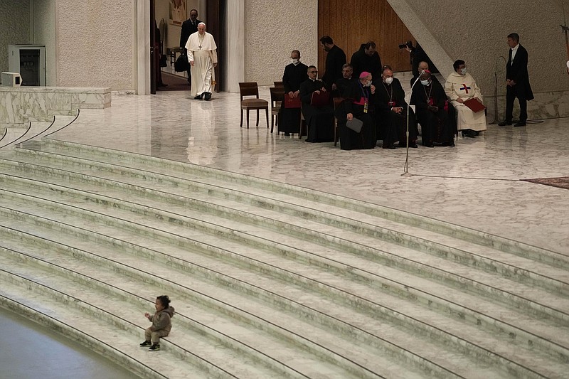 Pope Francis arrives for his weekly general audience as a child plays on the steps of the Paul VI Hall, at the Vatican, Wednesday, Dec. 22, 2021. (AP Photo/Alessandra Tarantino)