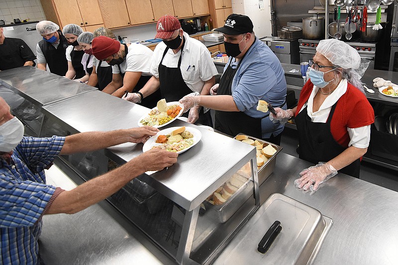 Volunteers and staff form serve plates of food Saturday during Christmas meal and giveaway at the Compassion Center in Little Rock.
(Arkansas Democrat-Gazette/Staci Vandagriff)