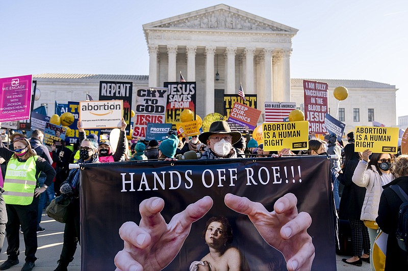 FILE - Stephen Parlato of Boulder, Colo., holds a sign that reads &quot;Hands Off Roe!!!&quot; as abortion rights advocates and anti-abortion protesters demonstrate in front of the U.S. Supreme Court, Dec. 1, 2021, in Washington.  President Joe Biden insists that he strongly believes in the rights spelled out in the 1973 Roe v. Wade court decision, which are now under the most dire threat in decades. But he barely uses the word &#x201c;abortion.&#x201d; And when his administration has been asked about what it can do to protect reproductive rights, the response has mostly been that Congress must write the landmark court decision into law, a strategy that is highly likely to fail. To the women who rallied to Biden&#x2019;s presidential campaign in no small part to protect the landmark court ruling, that&#x2019;s not nearly enough.  (AP Photo/Andrew Harnik, File)