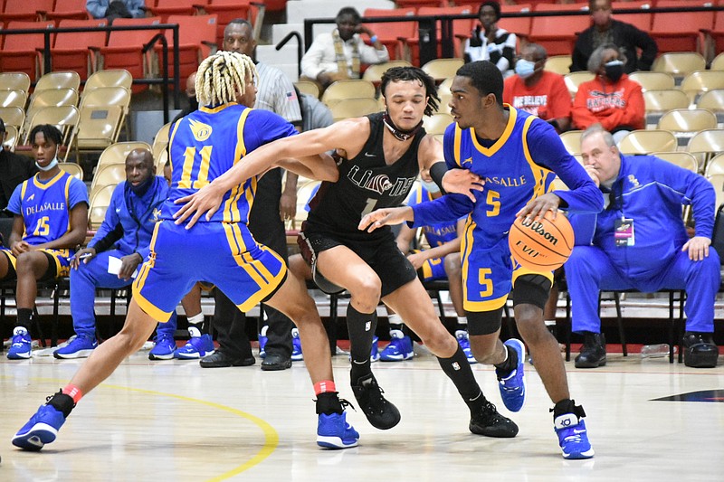 Mike Davis (5) of De La Salle dribbles around Braxton Stacker of Cardinal Ritter as Evan Jackson (11) sets a pick for Davis on Wednesday, Dec. 29, 2021, at the Pine Bluff Convention Center. (Pine Bluff Commercial/I.C. Murrell)