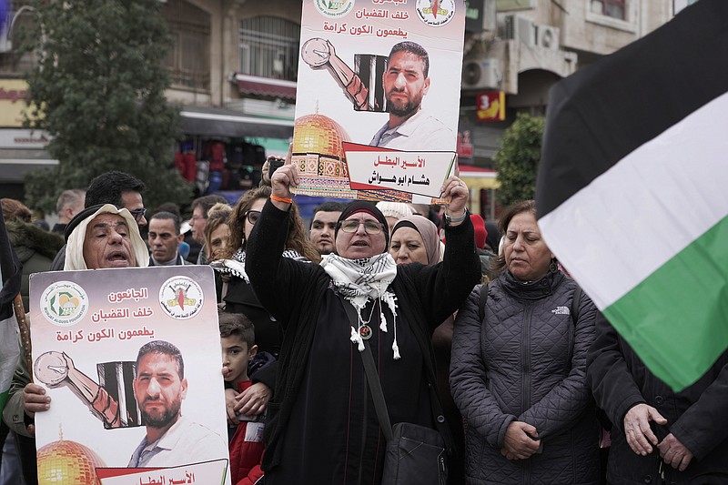 Palestinians attend a protest in solidarity with Hisham Abu Hawash, an Islamic Jihad member held by Israel under administrative detention, who staged a hunger strike for over 130 days, in the West Bank city of Ramallah, Sunday, Jan, 2, 2022. Israel's controversial policy of administrative detention allows suspects to be held without charge indefinitely. The banner in Arabic reads, &quot;Those starving behind bars feed the universe with dignity.&quot; (AP Photo/Majdi Mohammed)