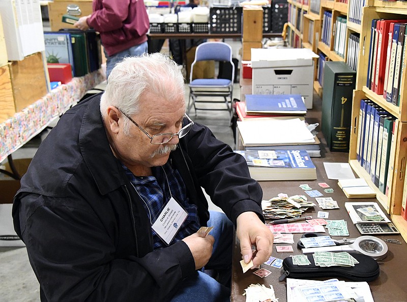 Charlie Adams, of Texas, sorts through stamps he offered for sale at the Tri-Lakes Coin Show in 2019. - The Sentinel-Record file photo