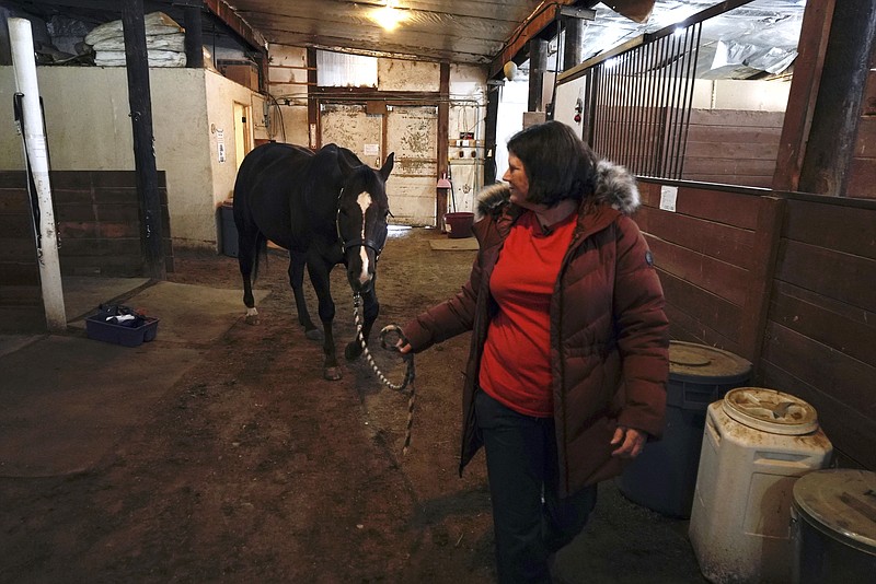 Lisa Young walks her horse, Foxy, Wednesday, Jan. 5, 2022, in Golden, Colo. She lost her home in the grass fires that hit Boulder County last week, and likely lost her two cats as well. Taking care of her horse gives her some semblance of normalcy, she said. (AP Photo/Brittany Peterson)