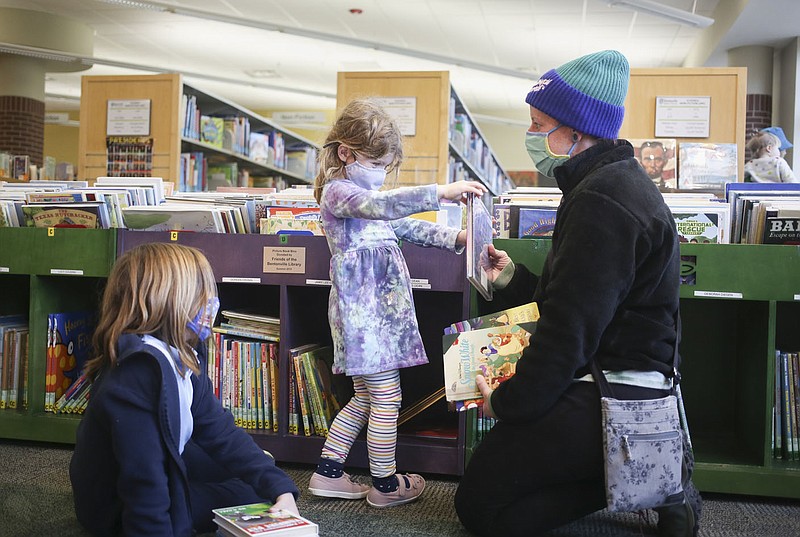 Caption: Kate Voss, 8, of Bentonville (from left) looks on as Paige Voss, 3, picks out books to show Sam Arsenault, Thursday, January 6, 2021 at the Bentonville Public Library in Bentonville. The schematic design for the Library expansion is nearing completion. (NWA Democrat-Gazette/Charlie Kaijo)