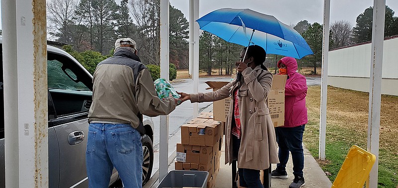 Chicot Elementary School Counselor Adrienne Hawkins, with Umbrella, and Chicot community school coordinator Nicole Chandler help distribute boxes of donated food to Chicot families just before holidays. (Arkansas Democrat-Gazette/Cynthia Howell).