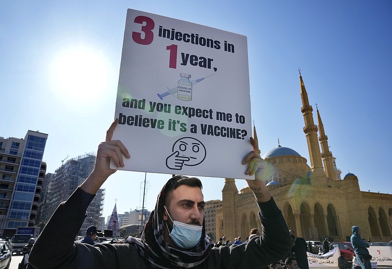 A protester holds a placard during a rally to protest measures imposed against people who are not vaccinated, in Beirut, Lebanon, Saturday, Jan. 8, 2022. Vaccination is not compulsory in Lebanon but in recent days authorities have become more strict in dealing with people who are not inoculated or don&#x2019;t carry a negative PCR test. (AP Photo/Hussein Malla)