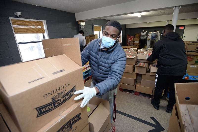 Brandus Mitchell of Fayetteville counts the contents of cases of food  while preparing for a distribution in 2021 at St. James Missionary Baptist Church in Fayetteville honoring Martin Luther King Jr., hosted by the Northwest Arkansas MLK Council, the church and the University of Arkansas. (NWA Democrat-Gazette file photo/Andy Shupe)