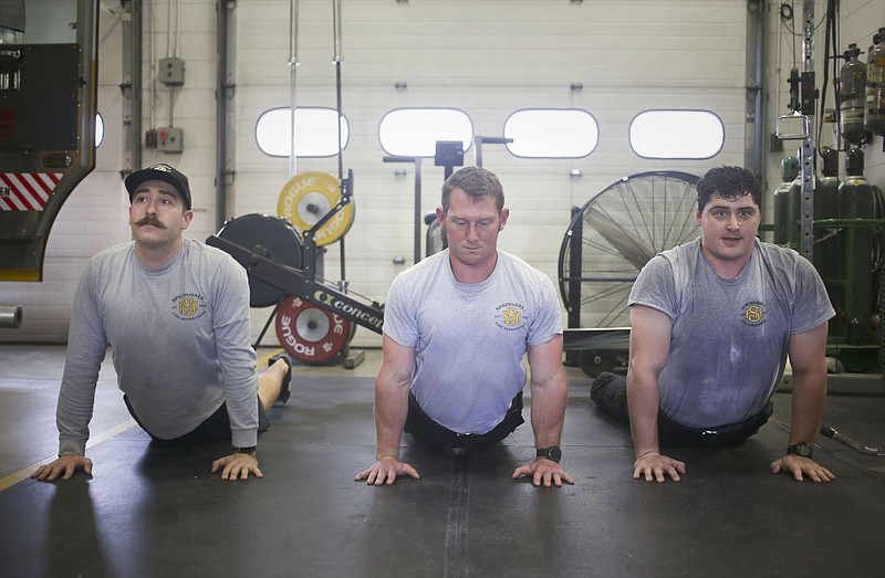 Capt. Rance Richardson (from left) of the Springdale Fire Department, driver/operator Noah Carter and probationary firefighter Dylan McDonald practice yoga Saturday at Fire Station 4 in Springdale. The Springdale Fire Department has since the first of the year operated on a 48/96 shift - 48 on, 96 off or 2 days on, 4 days off. Check out nwaonline.com/220110Daily/ for today's photo gallery. 
(NWA Democrat-Gazette/Charlie Kaijo)