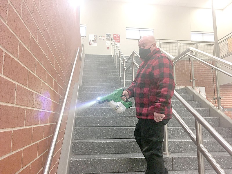COURTESY PHOTO
Jon Purifoy, principal of Farmington High School, uses an electrostatic fog machine to disinfect high-touch areas on the stairway leading to the second floor of the high school building. Farmington School District last week reinstated its mask mandate because of a higher rate of covid-19 cases and and increased its daily disinfecting measures.
