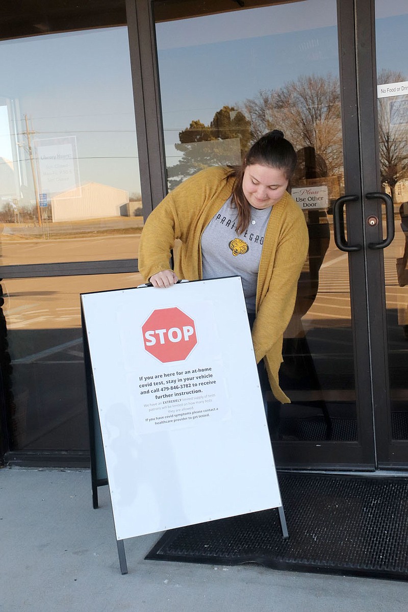 LYNN KUTTER ENTERPRISE-LEADER
Molly Hutchins, Prairie Grove Public Library assistant, places a sign out front in preparation for handing out rapid at-home covid-19 tests. Area libraries served as a distribution point for the tests last week. Prairie Grove required curbside pickup for the tests.