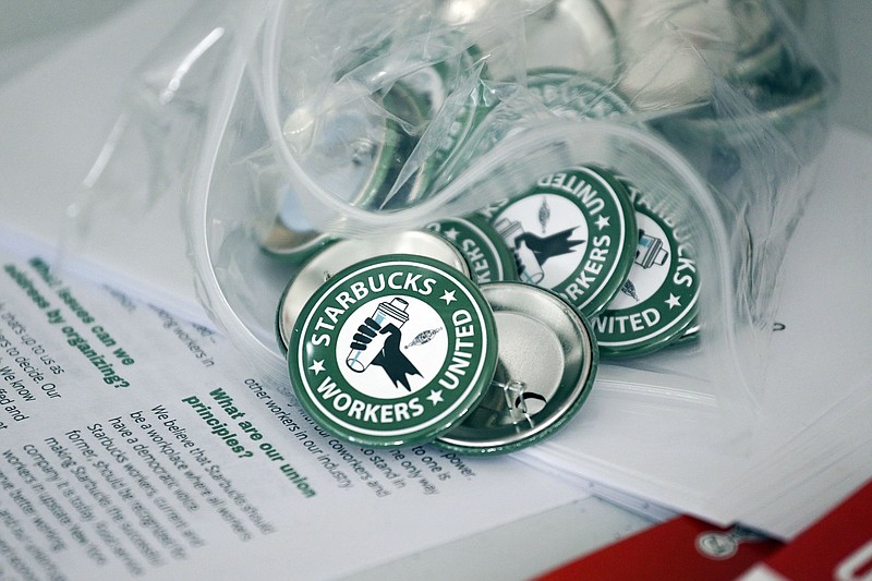 FILE - Pro-union pins sit on a table during a watch party for Starbucks' employees union election, Dec. 9, 2021, in Buffalo, N.Y. On Monday, Jan. 10, 2022, the National Labor Relations Board confirmed that a second Starbucks store near Buffalo has voted to unionize, one of a growing number of the coffee chain?s stores seeking to organize workers. (AP Photo, File)