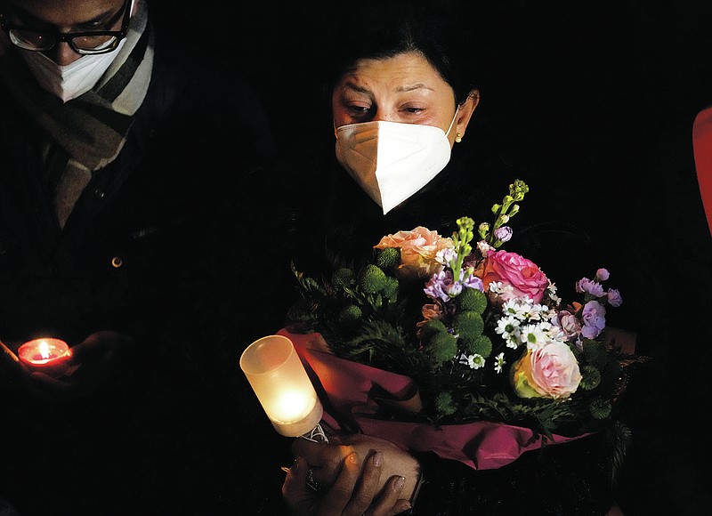Relatives of shipwreck victims, Concetta Virzi, who lost her sister Luisa Antonia, flanked at left by Kevin Rebello, who lost his brother Russel, hold candles during a commemoration on the 10th anniversary of the Costa Concordia cruise ship disaster, in the Tuscan island of Isola del Giglio, Italy, Thursday, Jan. 13, 2022. Italy on Thursday is marking the anniversary of the cruise ship disaster with a daylong commemoration, honoring the 32 people who died. (AP Photo/Andrew Medichini)