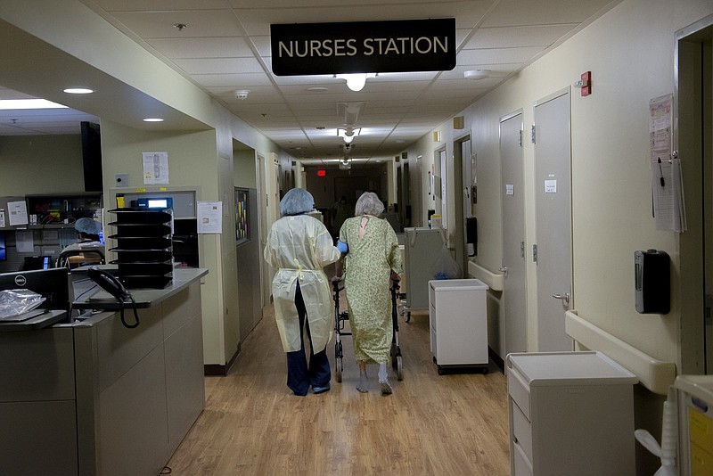 A nurse walks with a patient inside the Covid-19 ward at a hospital in Vancouver, Wash. MUST CREDIT: Bloomberg photo by Nathan Howard.