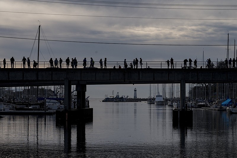 People watch waters rise in Santa Cruz harbor in Santa Cruz, Calif., Saturday, Jan. 15, 2022.  An undersea volcano has erupted in spectacular fashion near the Pacific nation of Tonga on Saturday.  Following the eruption, a tsunami advisory was issued for Hawaii, Alaska and the U.S. Pacific coast.(AP Photo/Nic Coury)