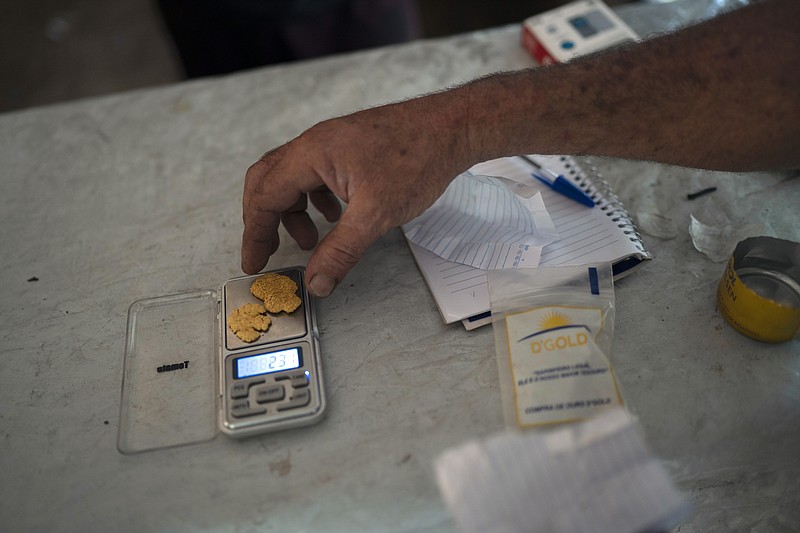 FILE - A gold miner weighs his weekly production at an illegal mine in the Amazon jungle, in the Itaituba area of Para state, Brazil, Aug. 22, 2020. Nuggets are spirited out of the jungle by prospectors to the nearest city where they are sold to financial brokers. (AP Photo/Lucas Dumphreys, File)