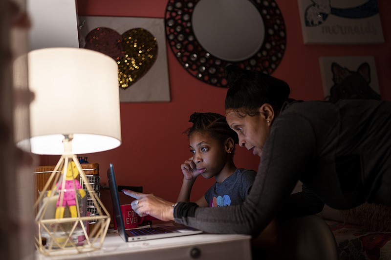 Abigail Schneider, 8, center, completes a level of her learning game with her mother April in her bedroom, Wednesday, Dec. 8, 2021, in the Brooklyn borough of New York. &quot;I'm determined to push and push to get them the things that help them,&quot; said April Schneider. &quot;I have to go above and beyond to make sure whatever requirements they need they get.&quot; (AP Photo/John Minchillo)