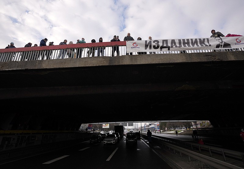 Environmental demonstrators hold banner showing an image of Serbian President Aleksandar Vucic, reading: &quot;A traitor!&quot;  as they block a highway during a protest in Belgrade, Serbia, Saturday, Jan. 15, 2022. Hundreds of environmental protesters demanding cancelation of any plans for lithium mining in Serbia took to the streets again, blocking roads and, for the first time, a border crossing. Traffic on the main highway north-south highway was halted on Saturday for more than one hour, along with several other roads throughout the country, including one on the border with Bosnia. (AP Photo/Darko Vojinovic)