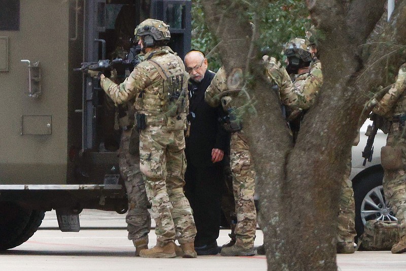 Shortly after 5 p.m., local time, authorities escort a hostage out of the Congregation Beth Israel synagogue in Colleyville, Texas, Saturday, Jan. 15, 2022. Police said the man was not hurt and would be reunited with his family. (Elias Valverde/The Dallas Morning News via AP)