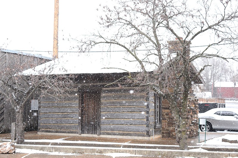 Westside Eagle Observer/MIKE ECKELS
Heavy snow begins to fall around the log cabin in downtown Decatur Saturday morning as Winter Storm Izzy starts to cover the roof and the ground around the structure. The storm dumped from three to five inches of snow by Sunday morning with higher amounts in the mountainous regions of Northwest Arkansas.